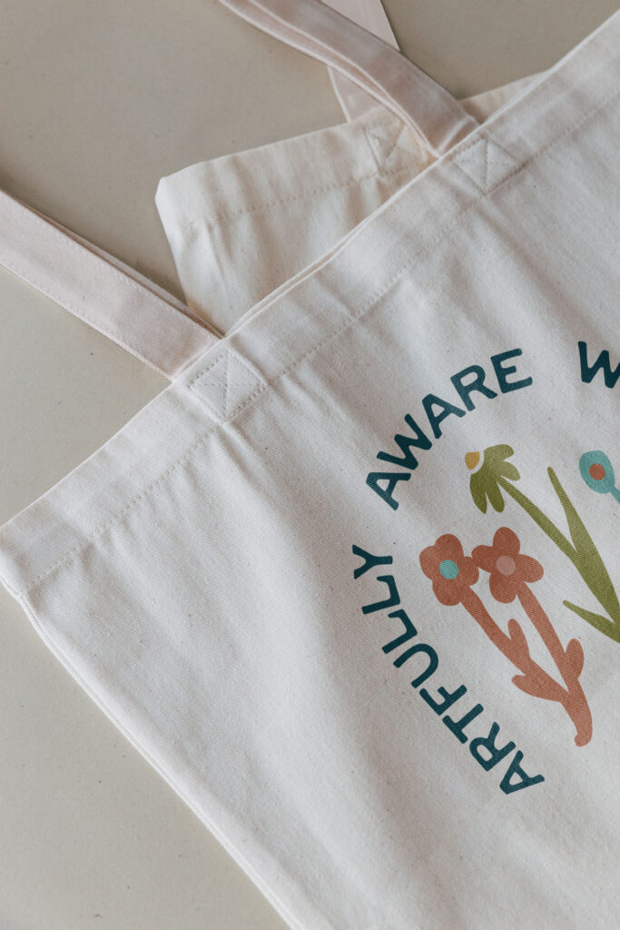 A tote bag printed with a colorful logo for an artist.