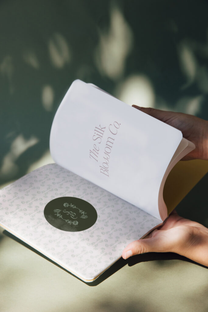 Notebook mockup featuring business name, logo sticker, and patterned paper.