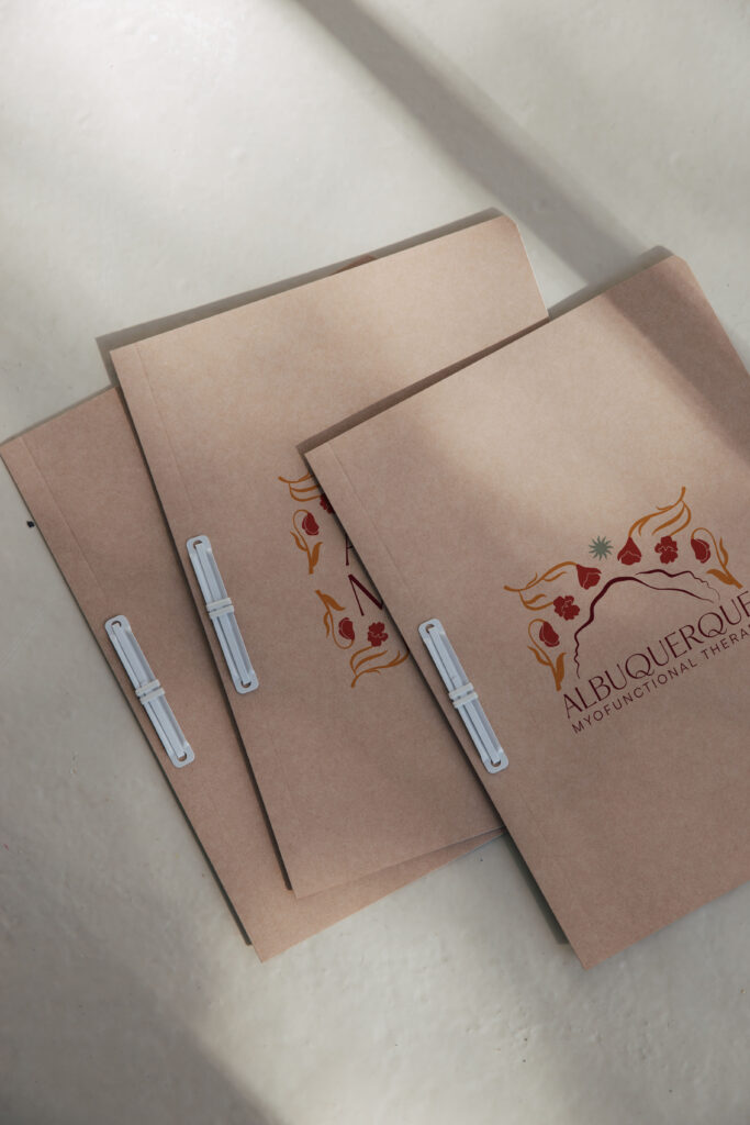 Brown folders featuring the Myofunctional Therapy logo design.