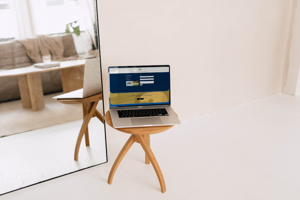 Laptop resting on a wooden stool displaying an insurance personal website