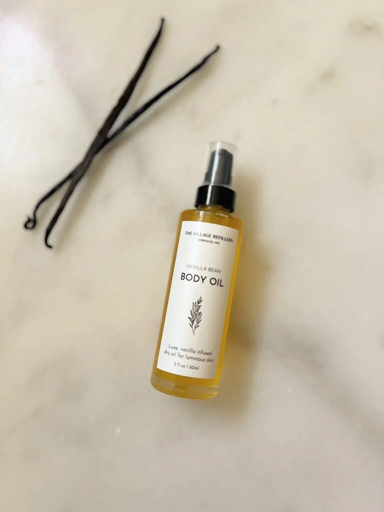 Minimalist product label on a body oil bottle with Village Refillery branding.