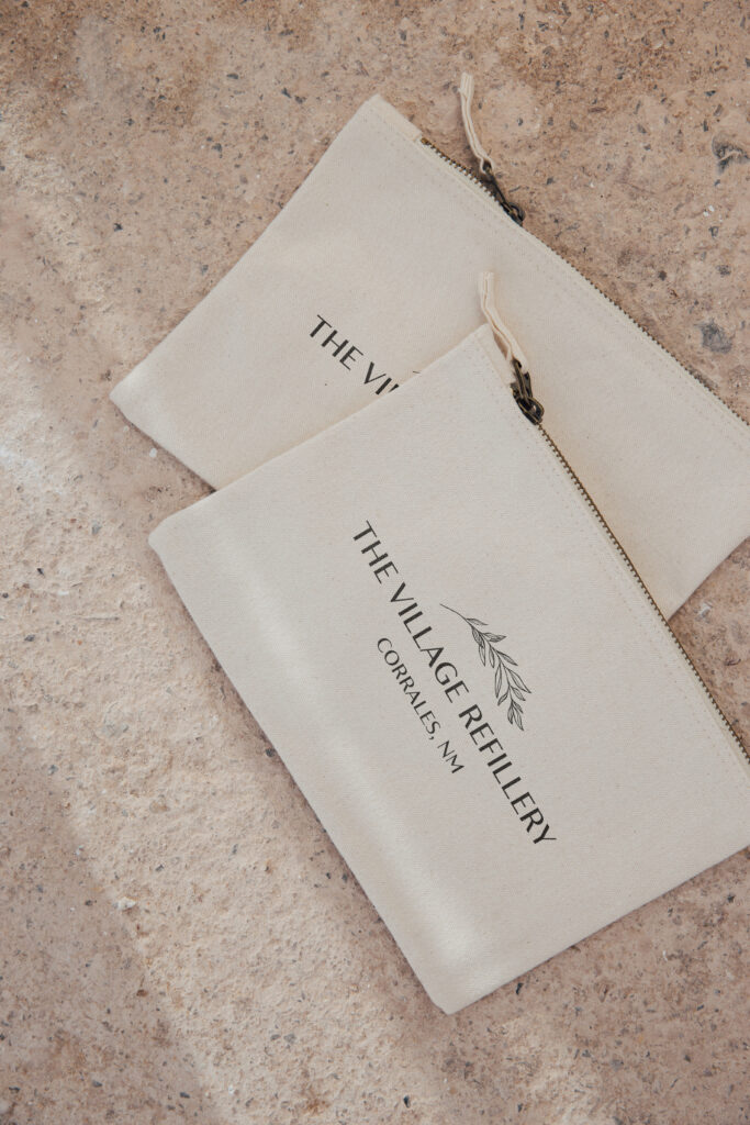 White minimalist pouch with the Village Refillery logo stamped on it.