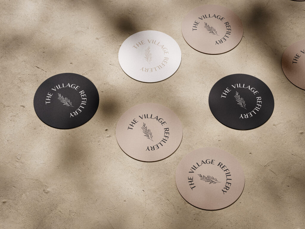 A set of round stickers featuring the Village Refillery logo.