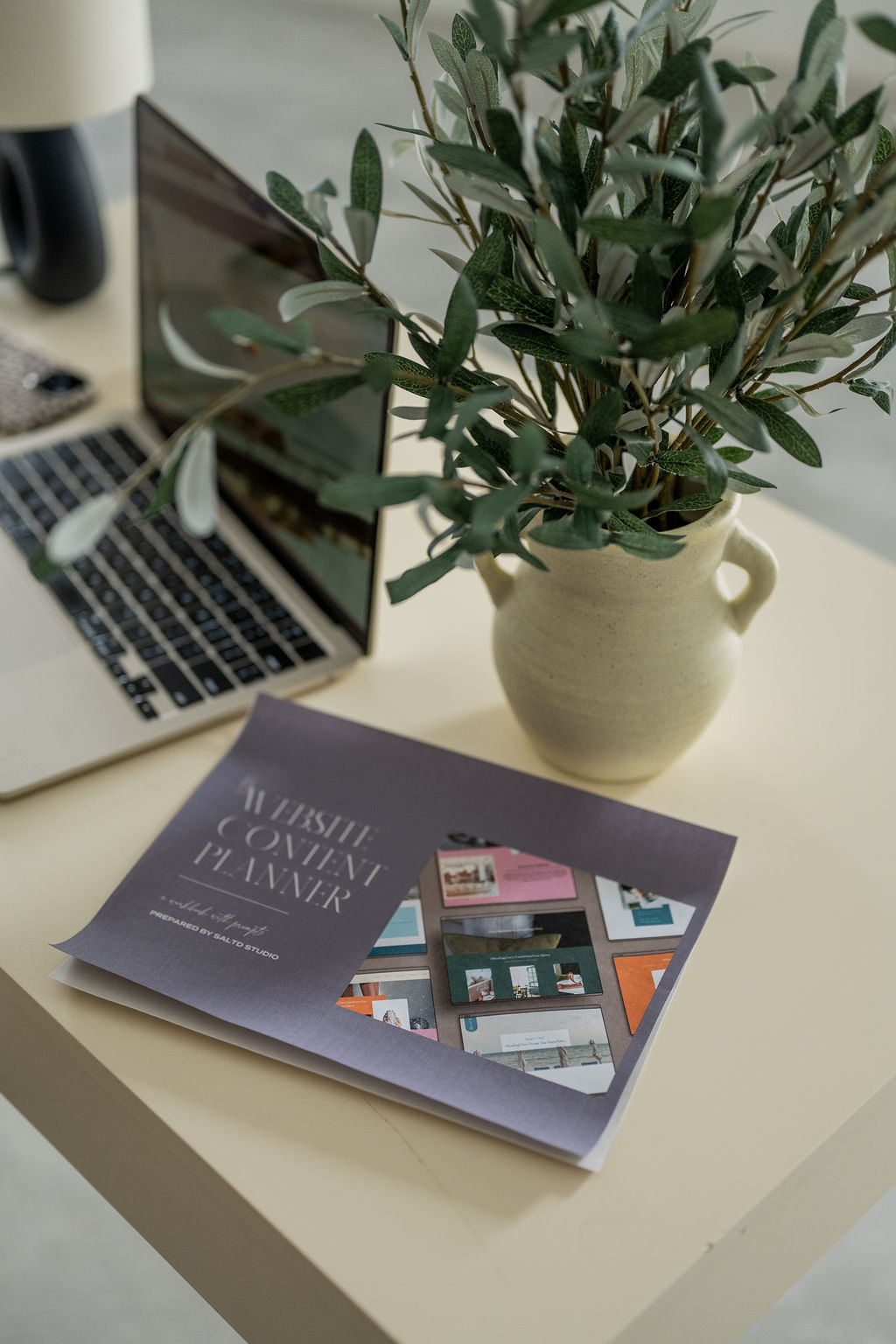 A laptop and printed website content planner on a desk.