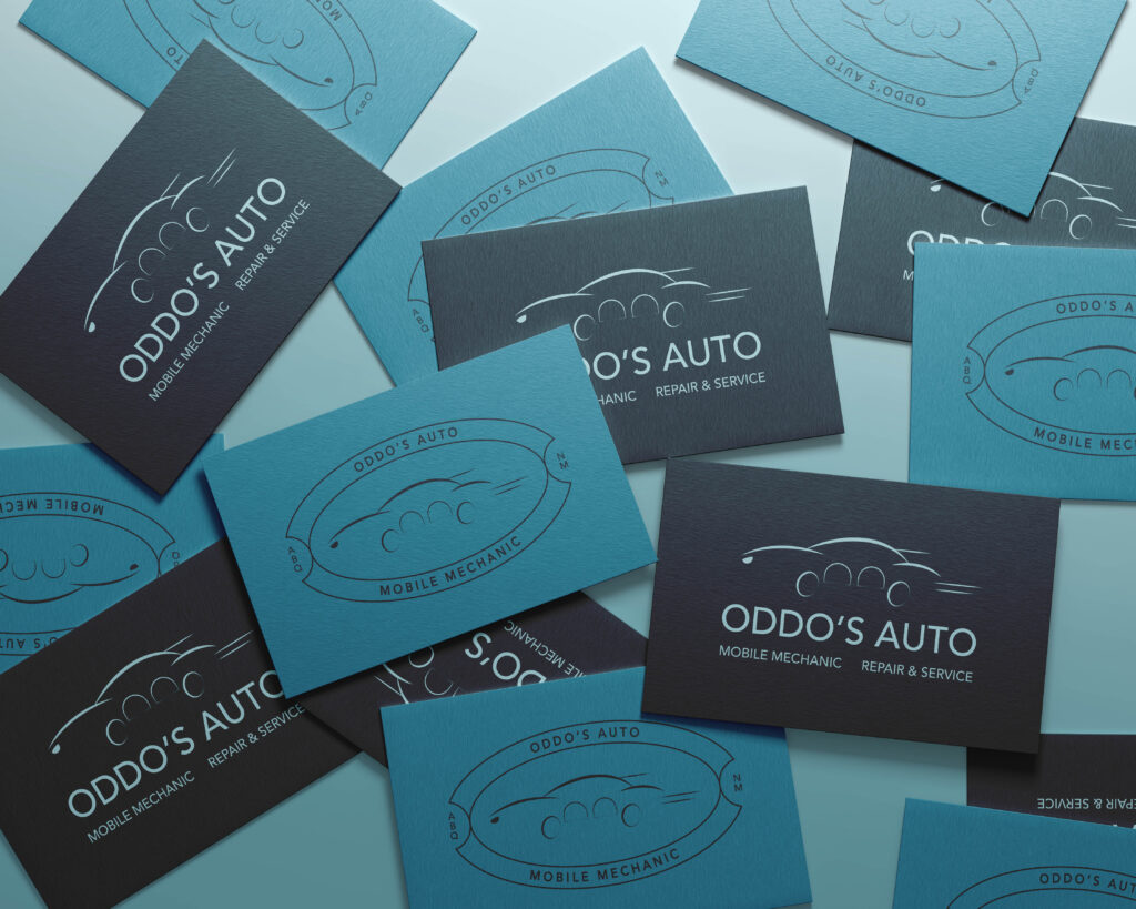 Cards embossed with the Oddo’s Auto logo, a mobile mechanic, scattered across a table.