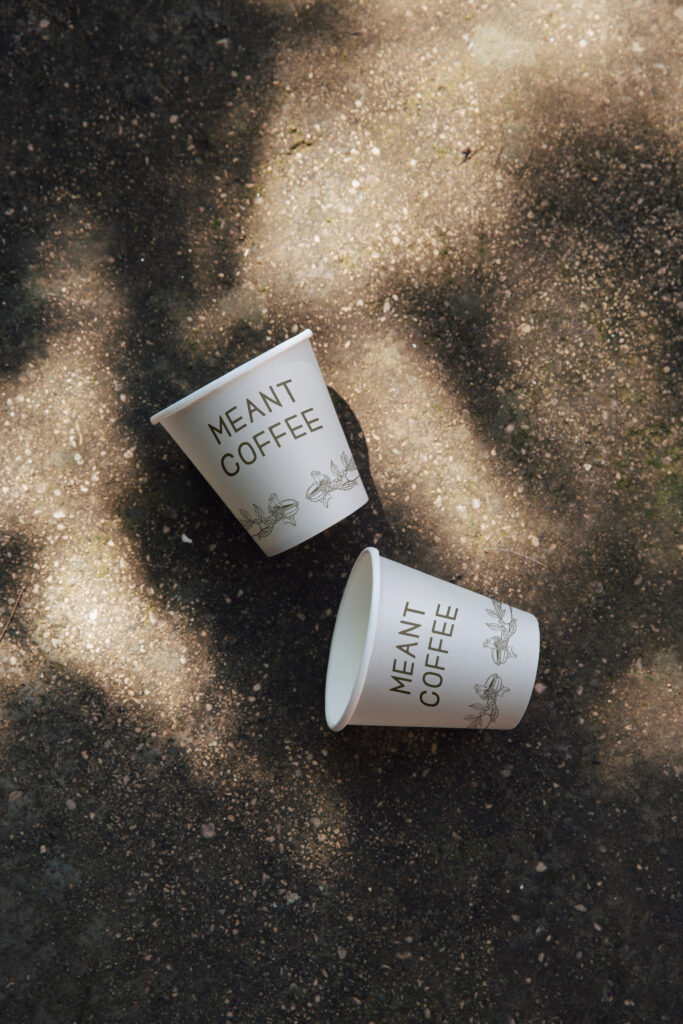The Meant Coffee logo design printed on coffee cups.
