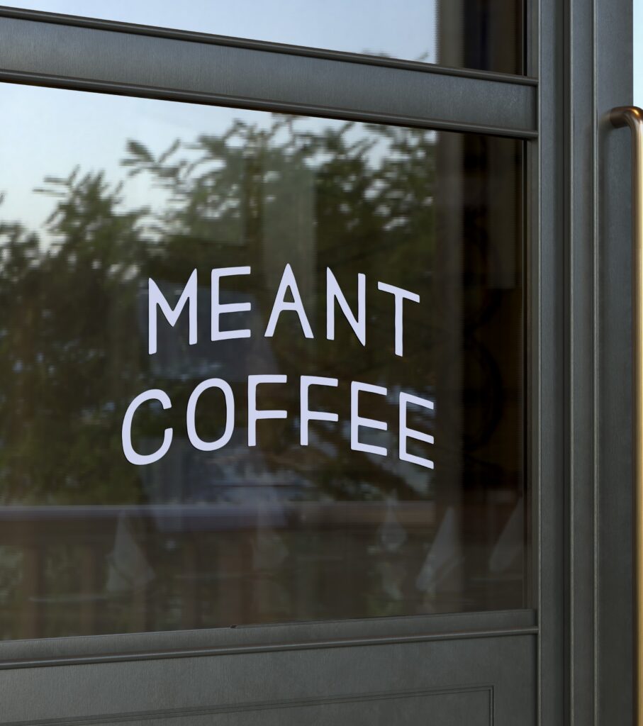 A coffee logo design displayed on a glass window.
